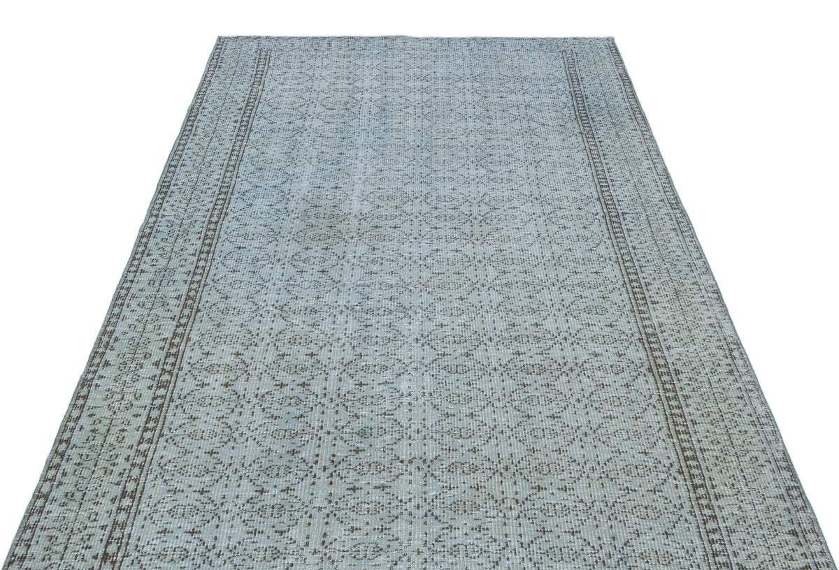 Light blue and brown rug with a repeating geometric lattice pattern and a bordered edge on a white background.