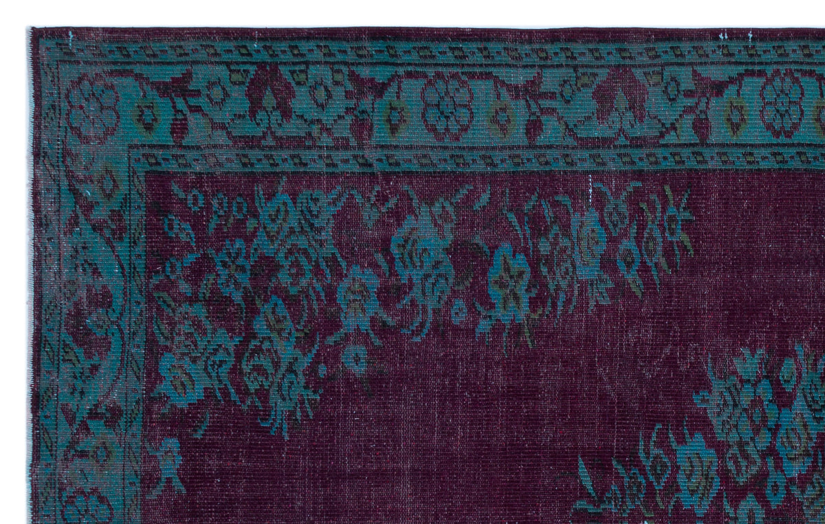 Deep purple rug with a teal floral border and distressed traditional pattern.