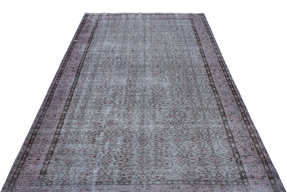 Distressed mauve and grey vintage-style rug with a traditional floral medallion pattern and a dark border.