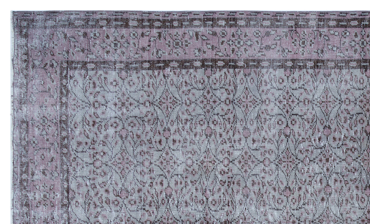 Distressed mauve and grey rug with a traditional floral medallion pattern and a dark border.