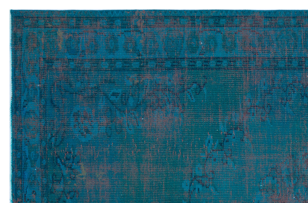 Teal and rust-colored distressed rug with a traditional border and faded floral pattern.