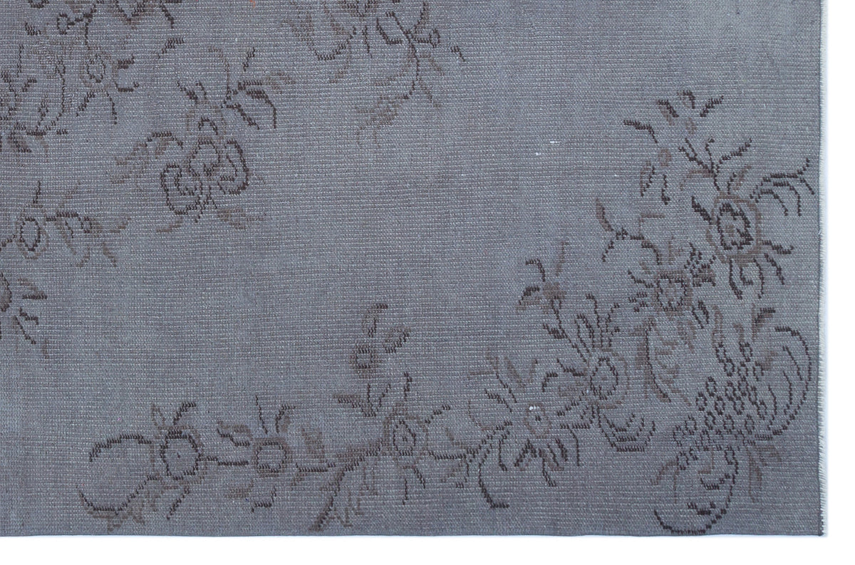Slate blue rug with a faded, dark grey floral vine pattern.