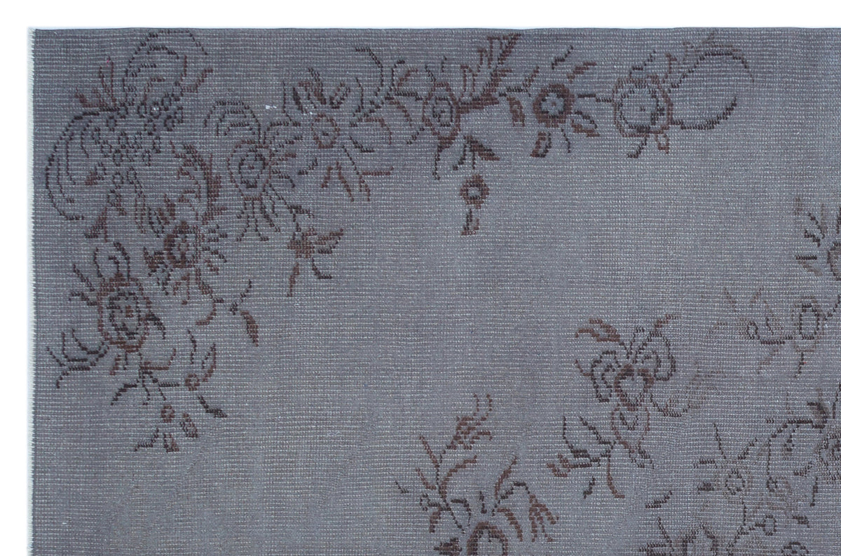 Grey rug with a dark brown floral vine pattern on a textured, woven background.