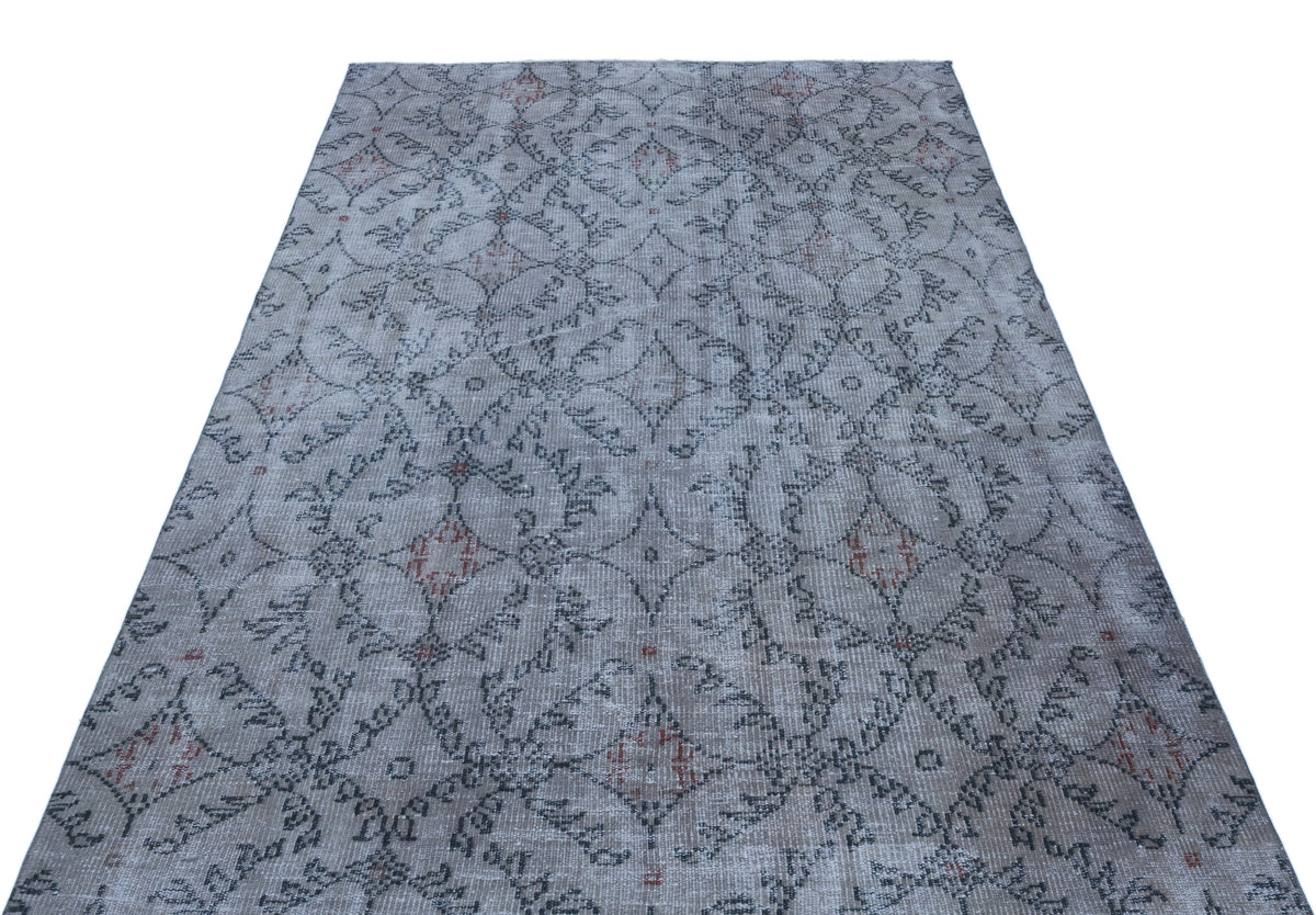 Grey and beige distressed rug with a repeating geometric diamond and floral lattice pattern.