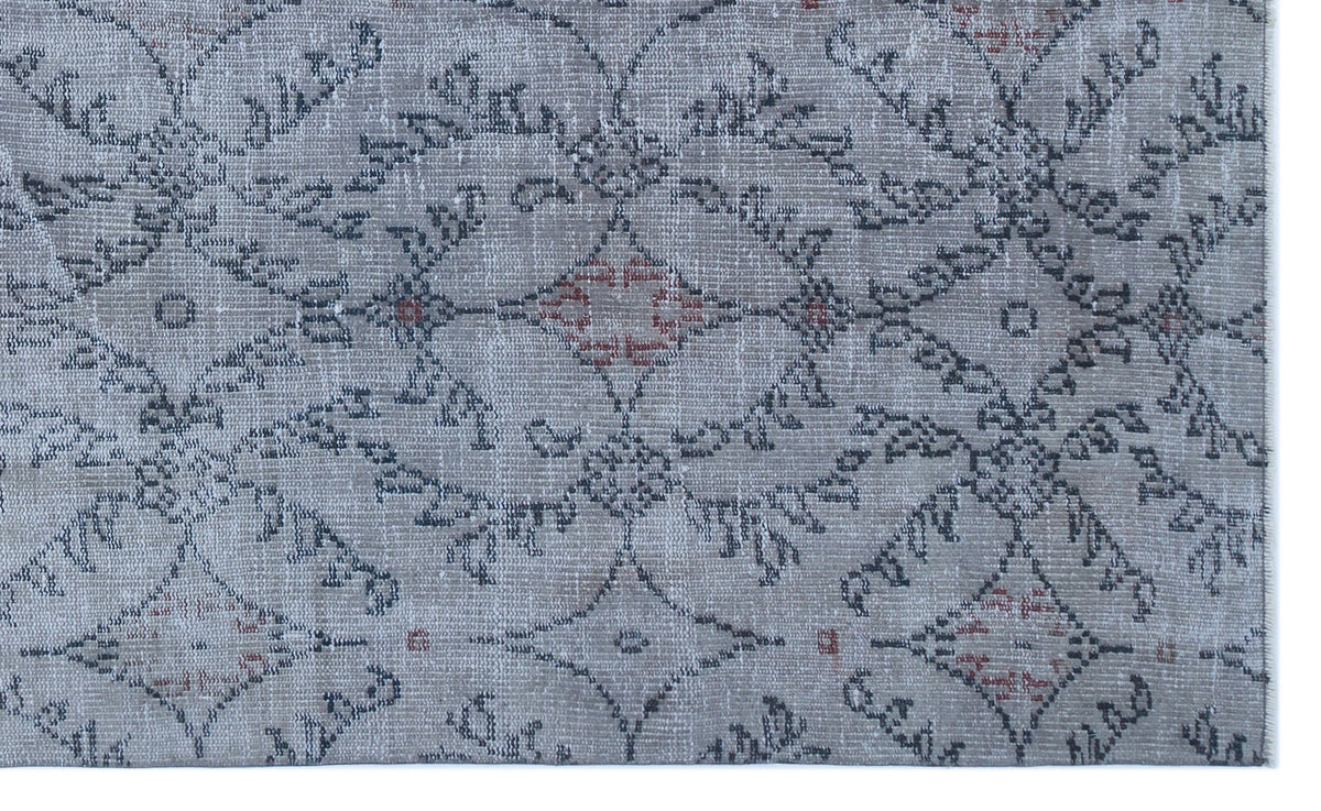 Grey rug with a distressed geometric lattice pattern featuring dark grey outlines and small red diamond accents.
