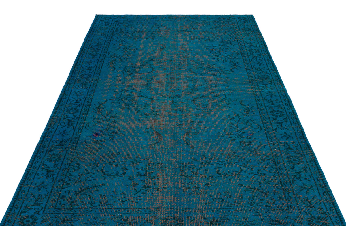 Teal distressed area rug with a dark floral medallion pattern and a wide border on a white background.