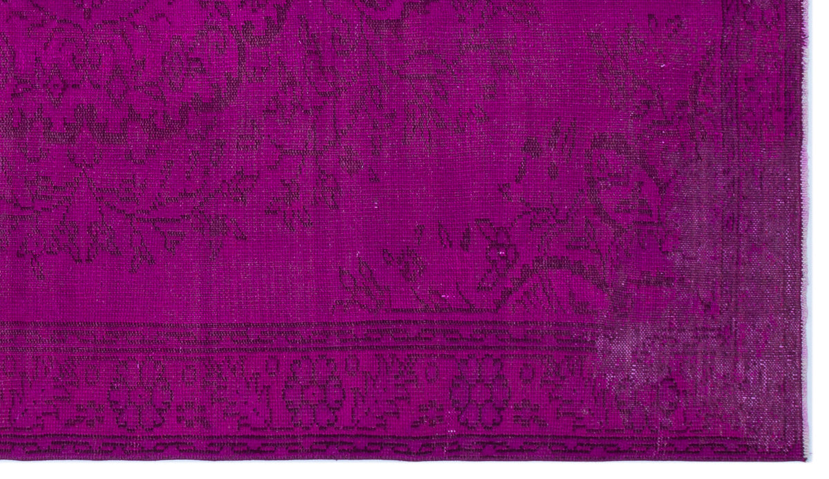 Magenta rug with a dark, distressed floral medallion pattern and a decorative border.
