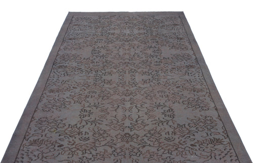 Load image 1 in gallery view. Dark grey and brown rug with a faded, intricate floral medallion pattern on a white background.