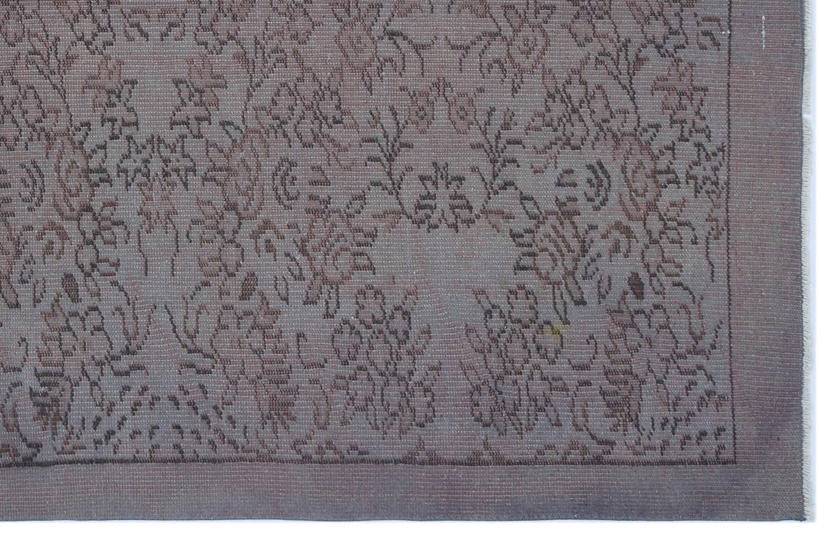 Muted mauve and brown rug with a traditional floral medallion pattern and a solid border.