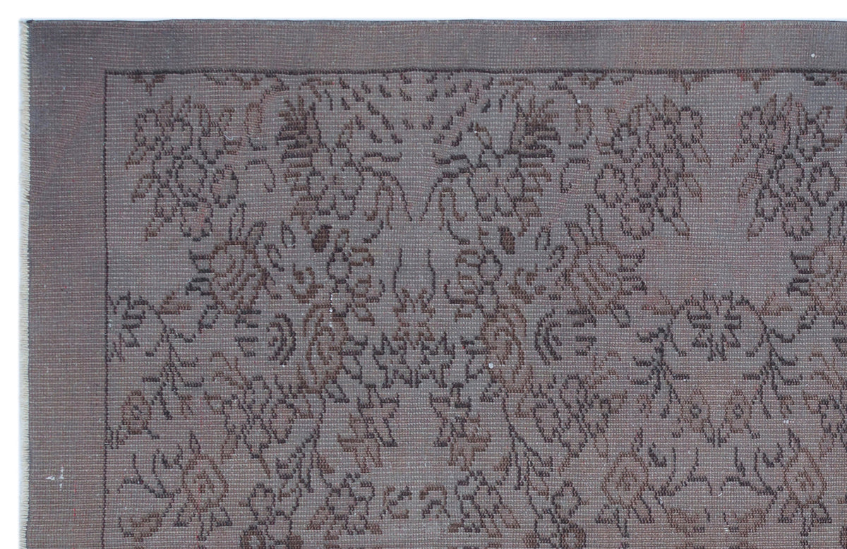 Dark brown monochromatic rug with a distressed, traditional floral medallion pattern and a simple border.