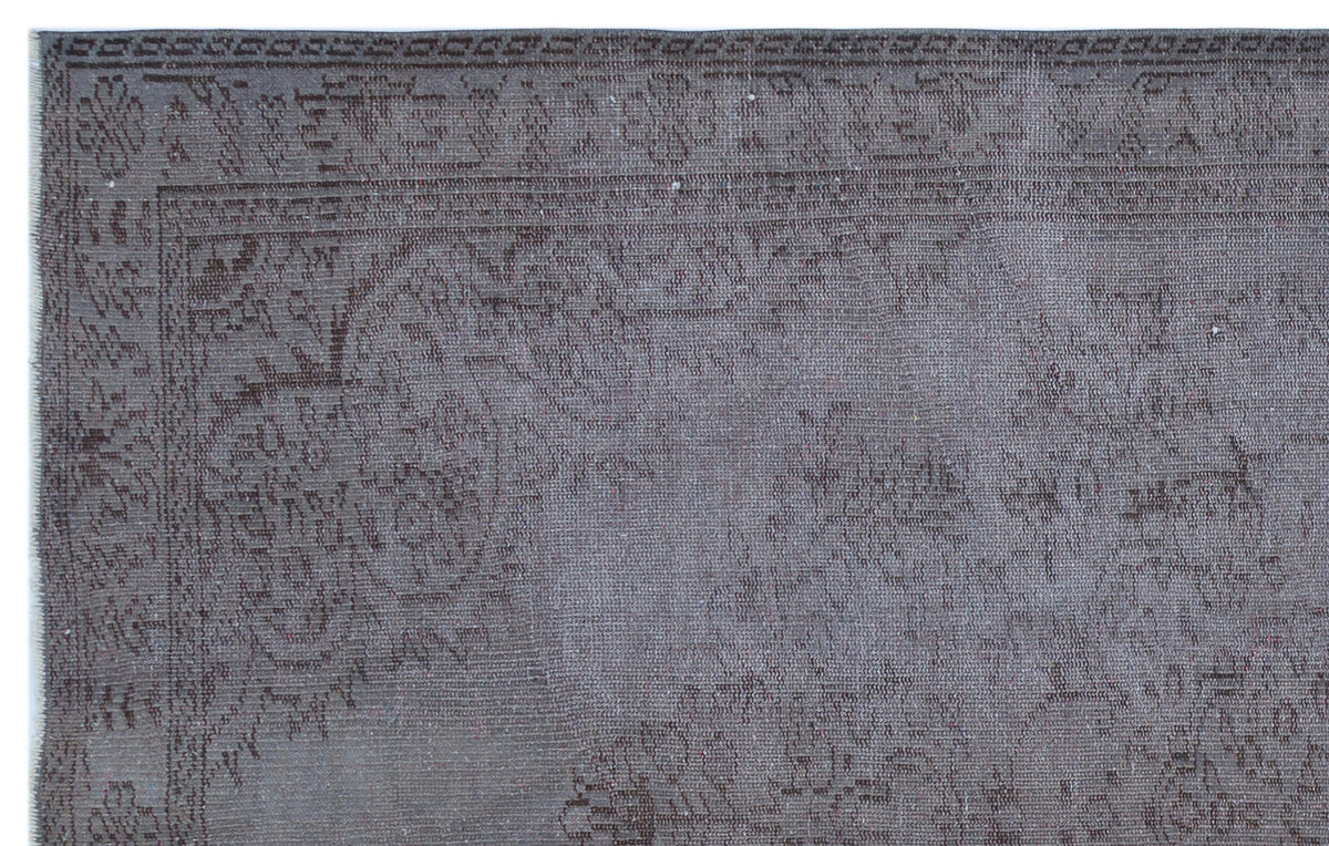 Charcoal grey rug with a faded, traditional floral medallion pattern and a detailed geometric border.