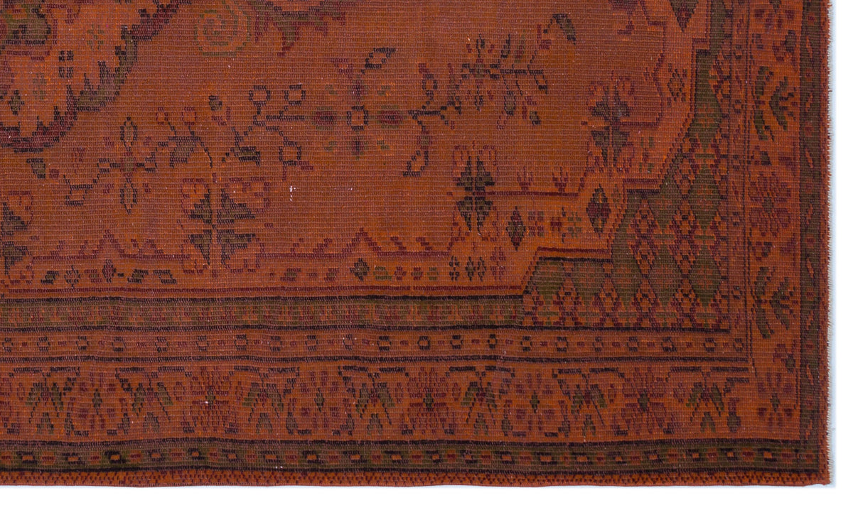 Rust-colored traditional rug with dark green geometric and floral motifs and a detailed border.