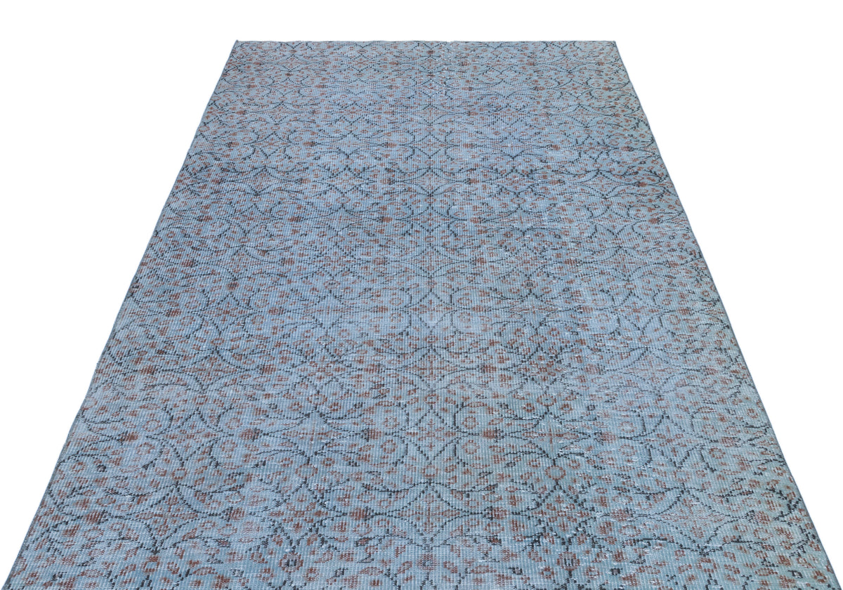 Light blue distressed rug with a dark grey and rust-colored repeating floral medallion pattern.