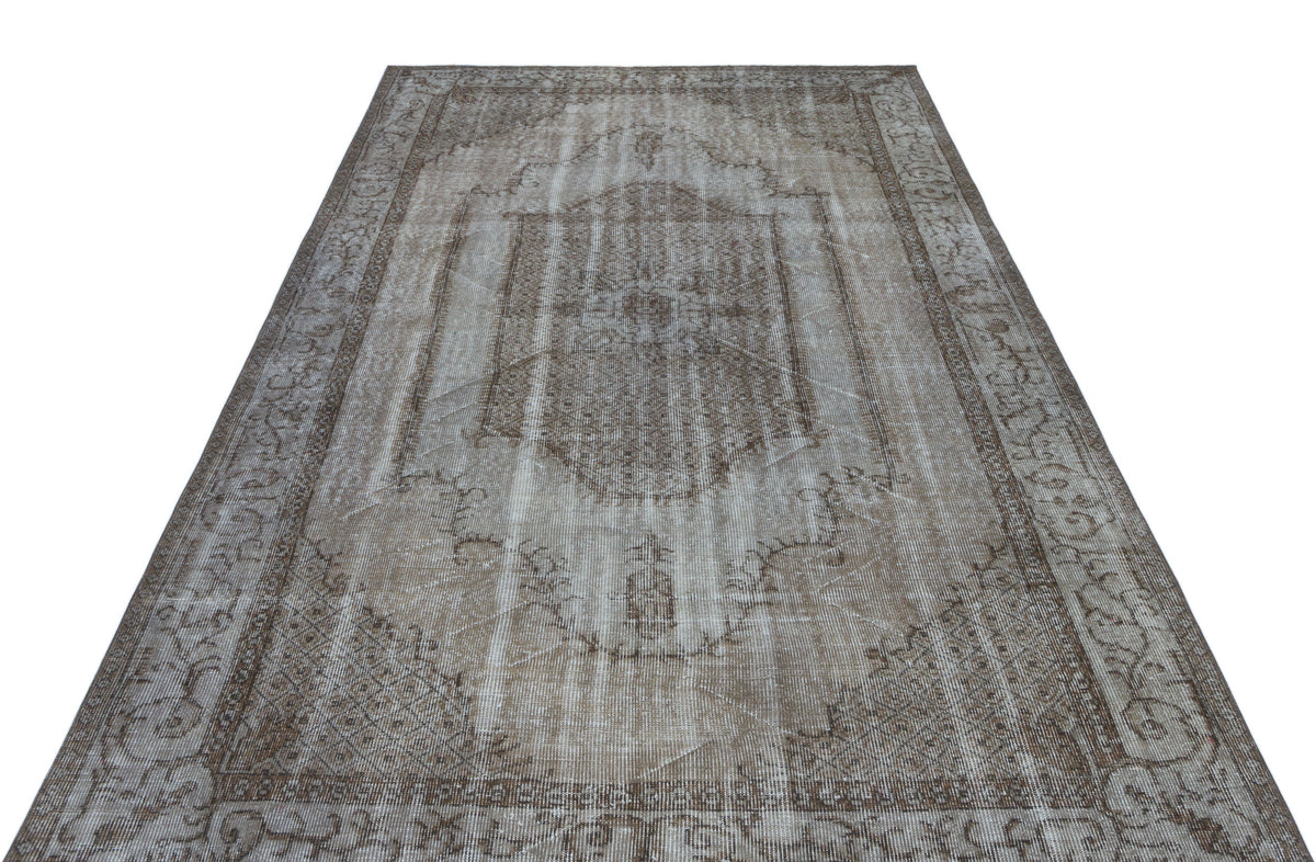 Distressed brown and beige vintage-style rug with a central medallion and ornate border on a white background.
