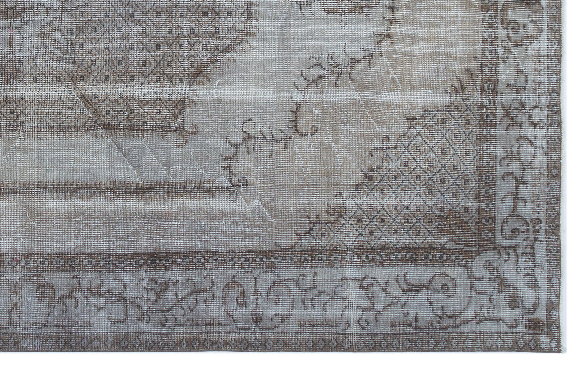 Distressed taupe and brown rug with a faded traditional medallion pattern and intricate geometric border.