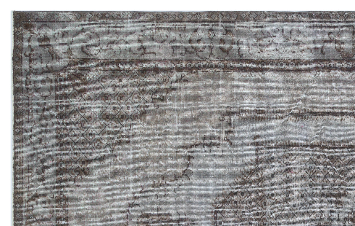 Distressed taupe and brown vintage-style rug with a faded traditional border and geometric medallion corner detail.