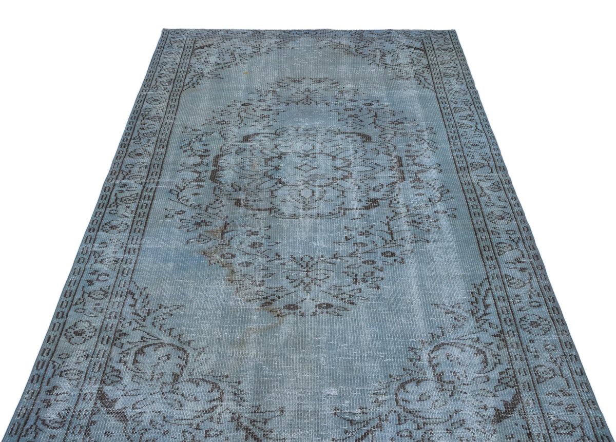Distressed light blue rug with a dark grey traditional floral medallion pattern and a decorative border.