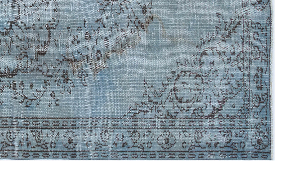 Light blue distressed rug with a dark brown floral medallion pattern and a geometric border.