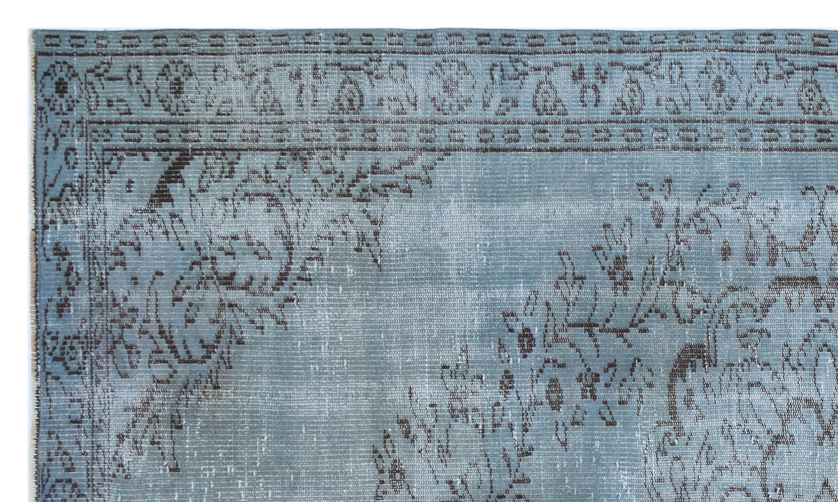 Dusty blue rug with a dark grey distressed floral medallion pattern and a decorative border.