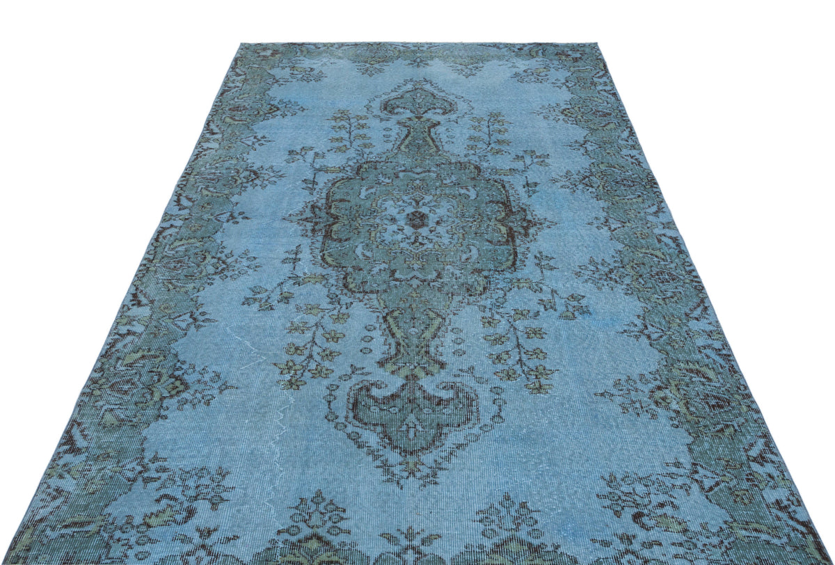 Light blue distressed rug with a dark grey central floral medallion and ornate border pattern.