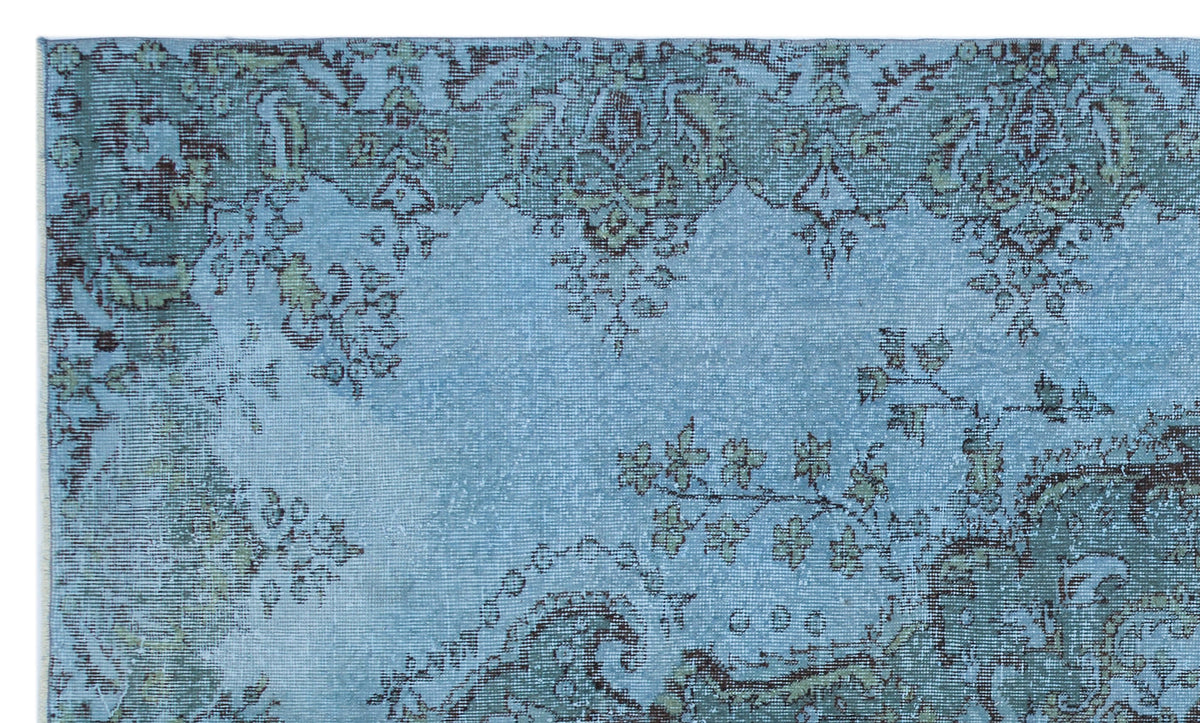 Light blue distressed rug with dark teal and sage green traditional floral medallion patterns.