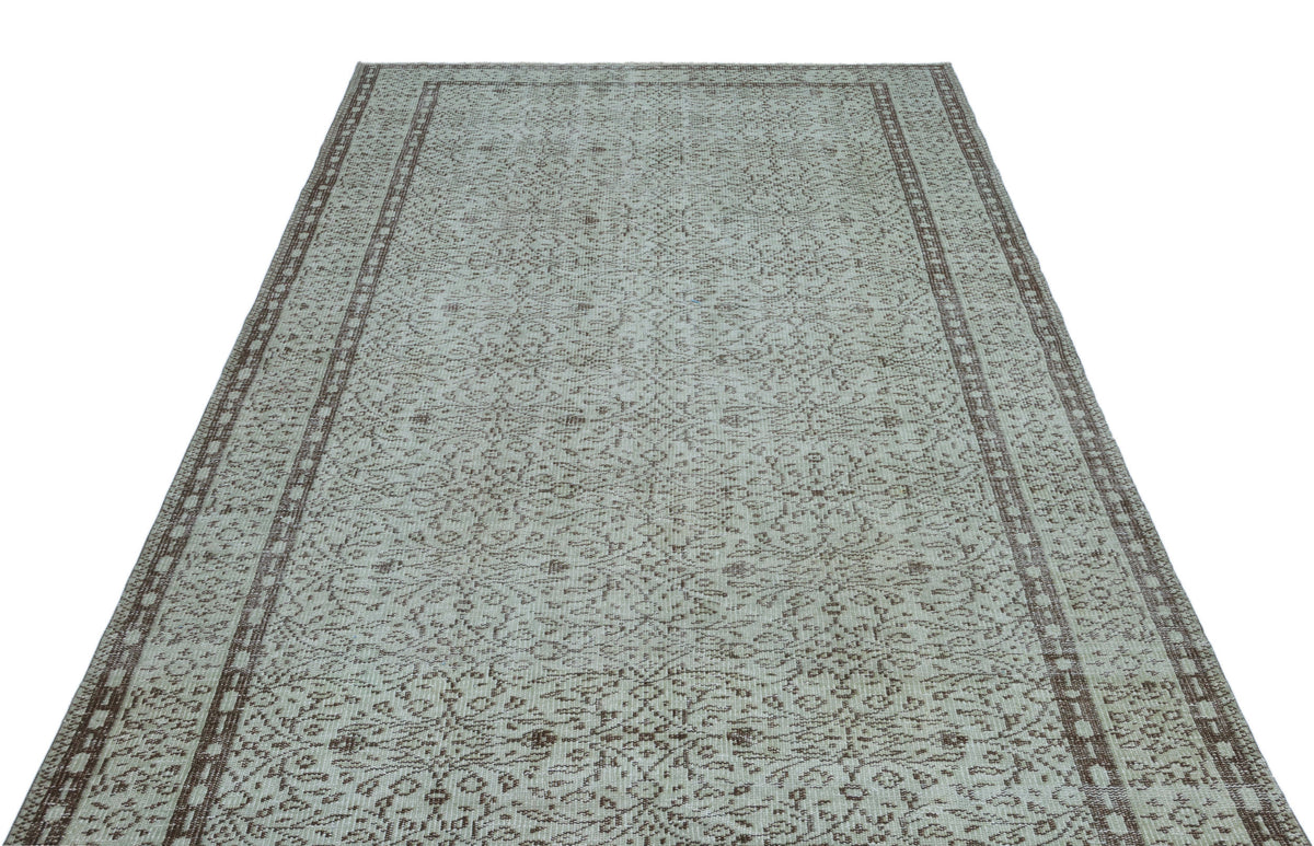 Light gray and brown vintage-style rug with an intricate floral medallion pattern and a double-bordered edge.
