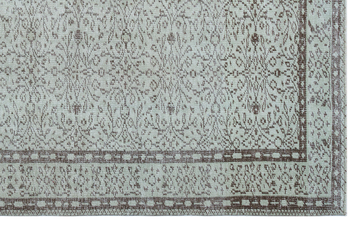 Light gray and brown rug with a distressed traditional floral medallion pattern and a geometric border.