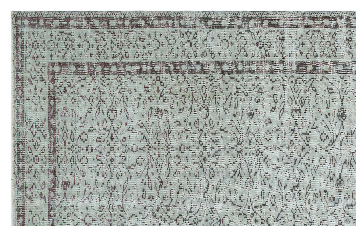 Light gray and taupe rug with a distressed traditional floral medallion pattern and a geometric border.