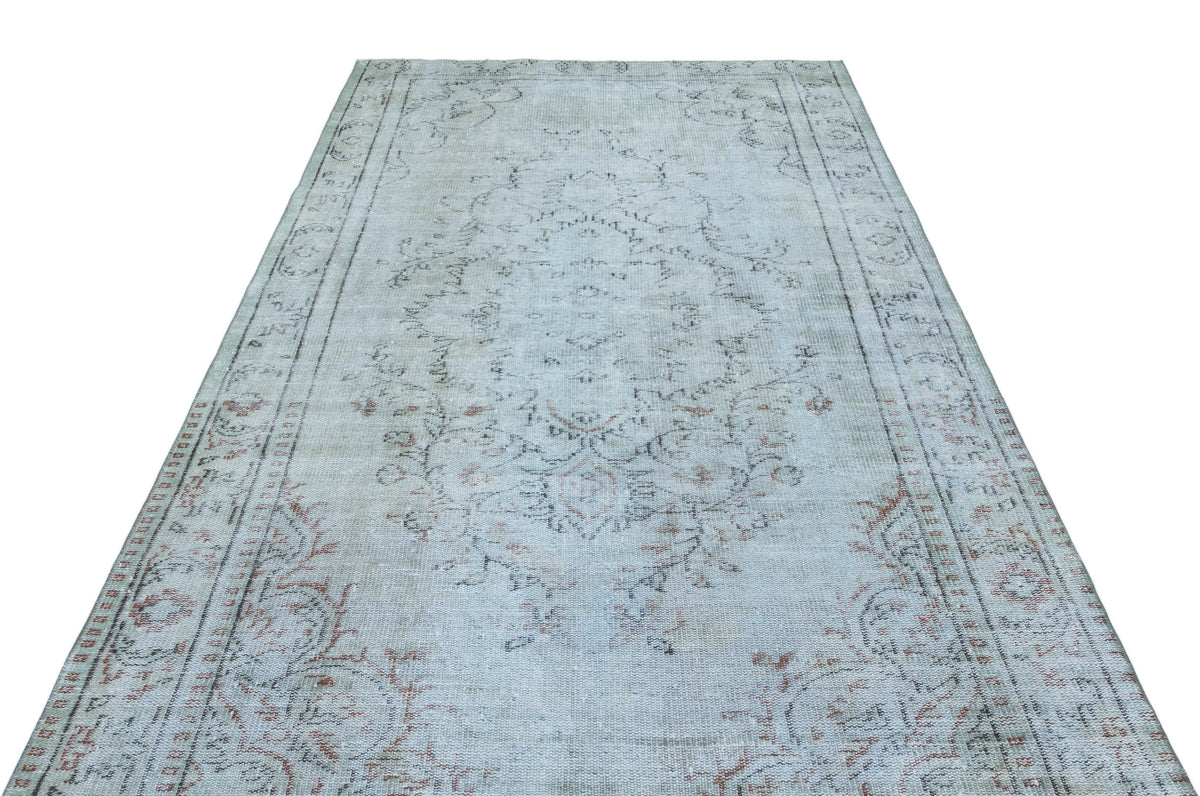 Light blue and beige vintage-style rug with a faded central medallion and ornate floral border.