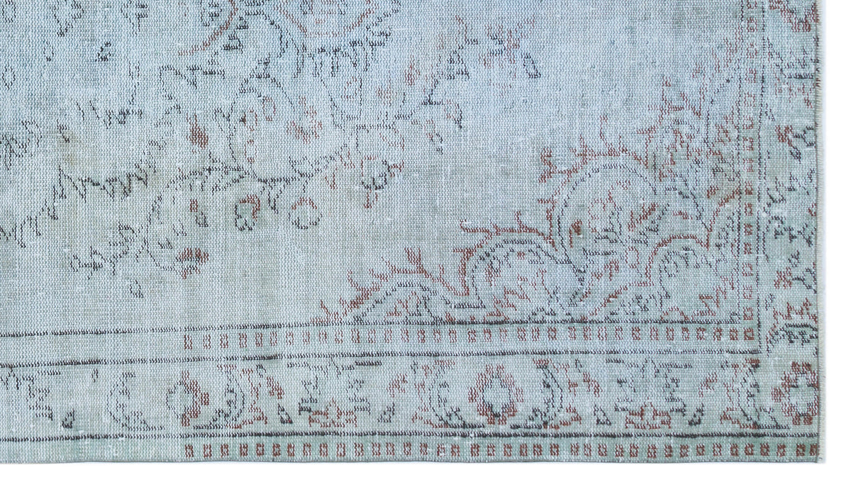 Light blue distressed rug with a faded floral medallion pattern in rust and charcoal on a white background.