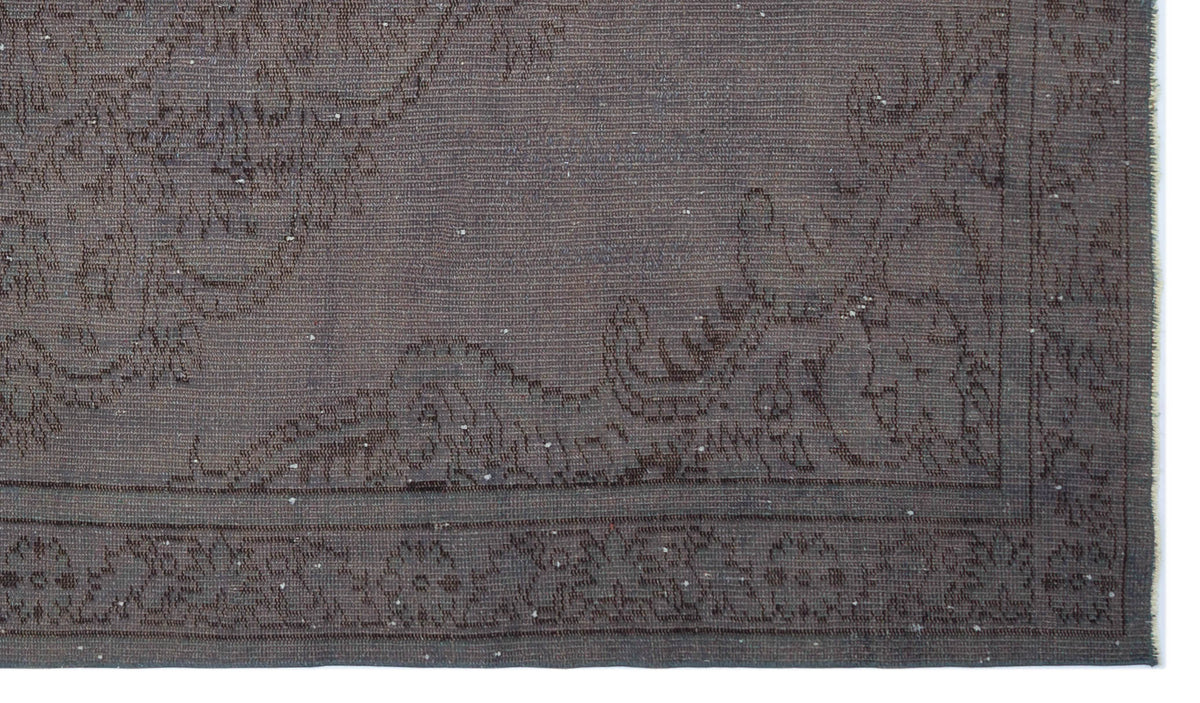 Dark charcoal grey rug with a subtle, tonal floral border and distressed, low-pile texture.