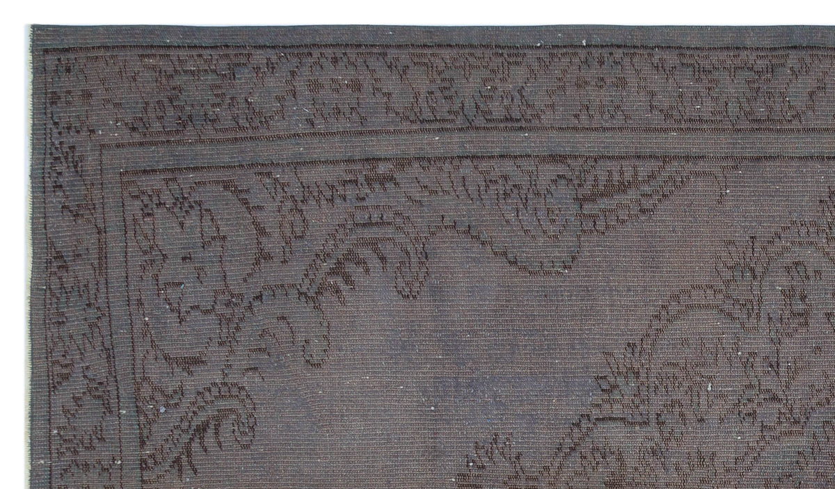 Dark charcoal rug with a subtle, tonal floral border and central medallion pattern.