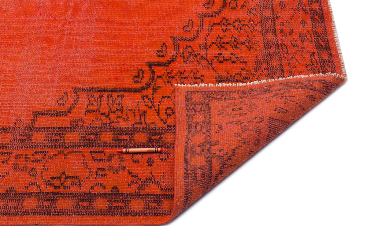 Bright orange rug with a dark brown traditional floral border, shown with a corner folded over on a white background.