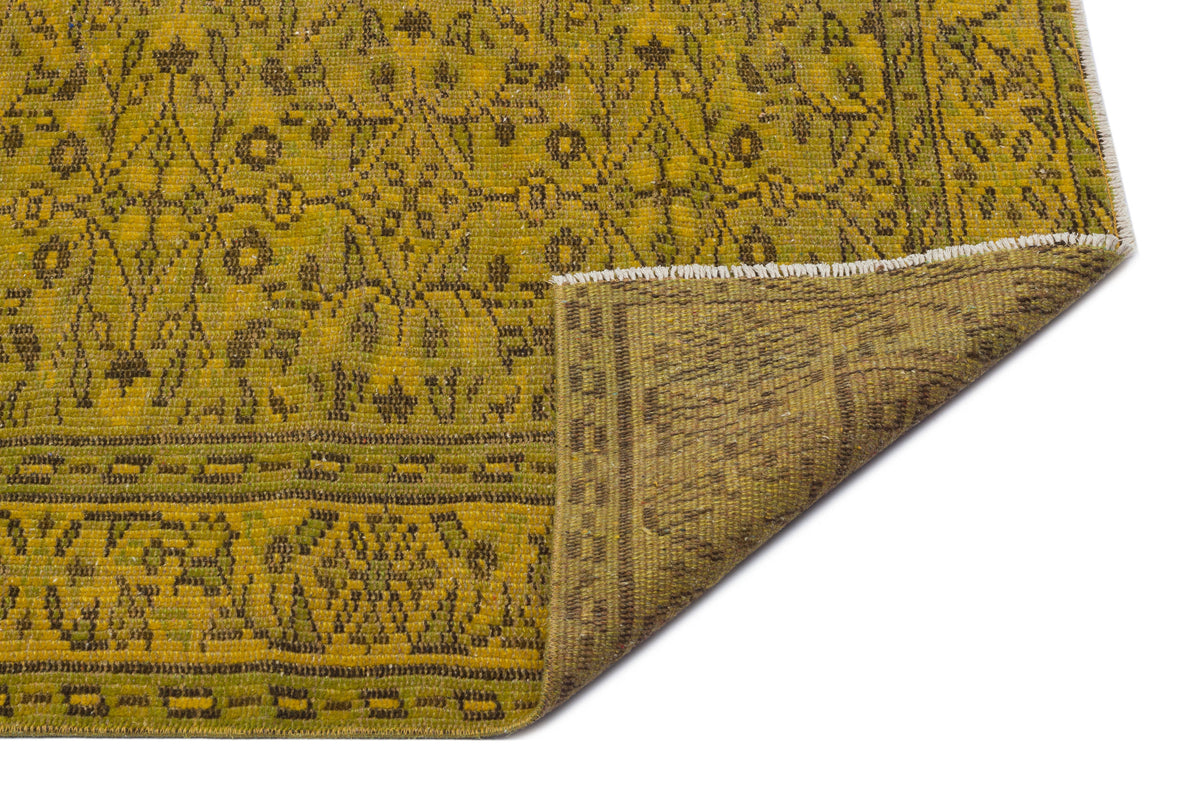 Mustard yellow and brown traditional rug with a floral medallion pattern, shown with a corner folded over.