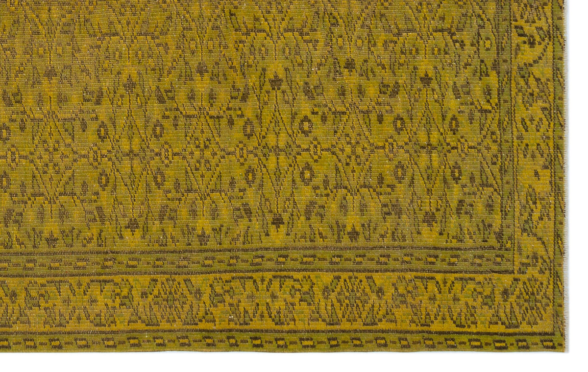 Olive green rug with a dark brown geometric lattice pattern and a decorative border.