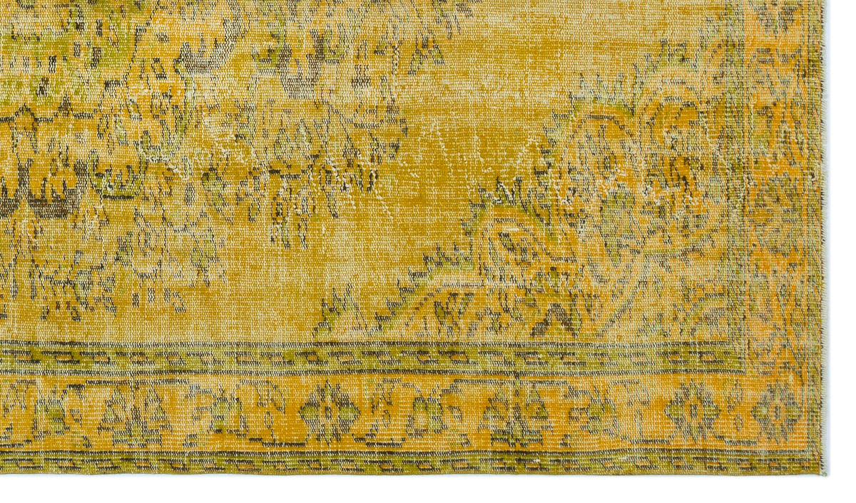 Mustard yellow and olive green distressed rug with a traditional floral medallion pattern and a geometric border.