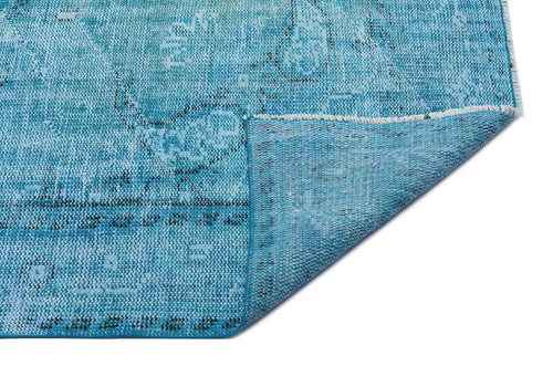 Load image 1 in gallery view. Distressed turquoise and blue rug with a faded traditional pattern, shown with a corner folded over on a white background.
