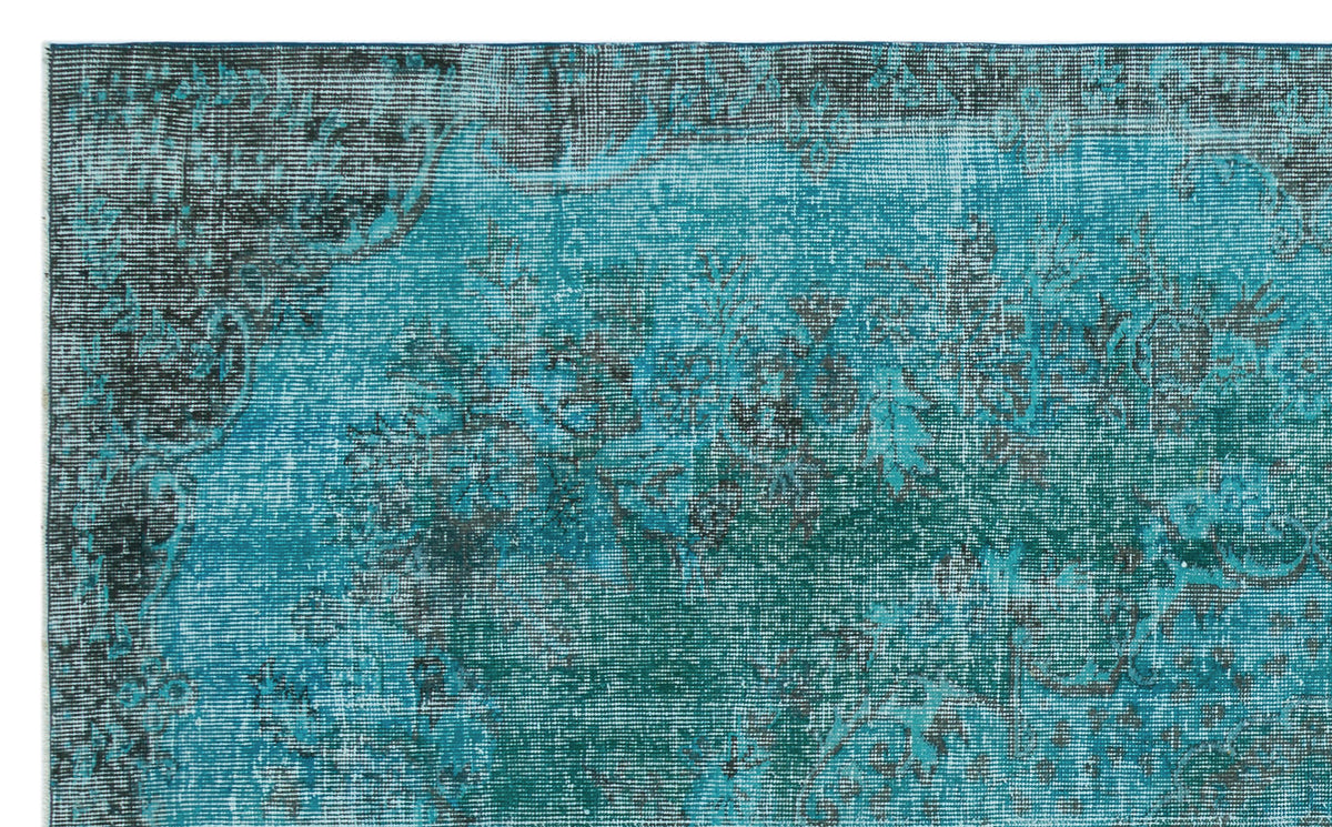 Teal and black distressed rug with a faded traditional floral pattern.
