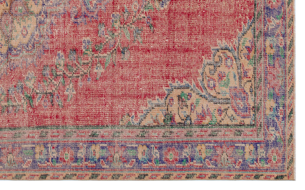 Red, blue, and beige vintage-style rug with a distressed floral medallion pattern and a decorative border.