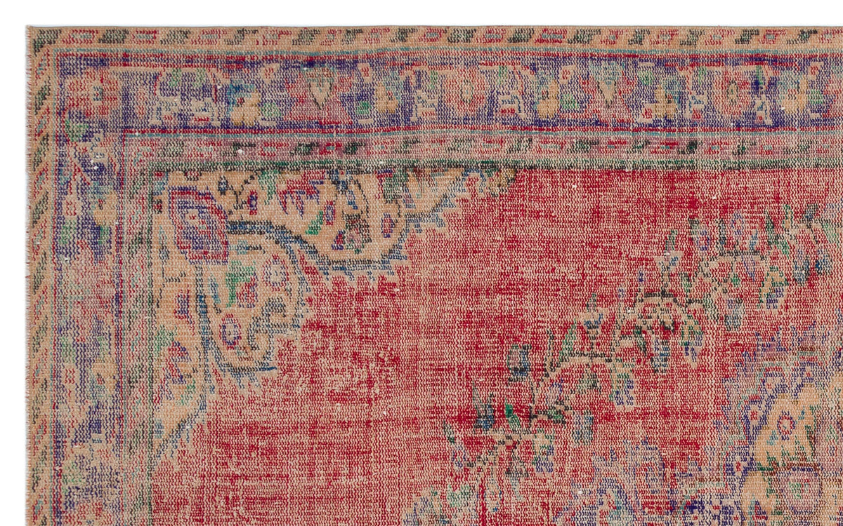 Distressed red, beige, and blue traditional rug with a faded floral medallion border and intricate woven texture.