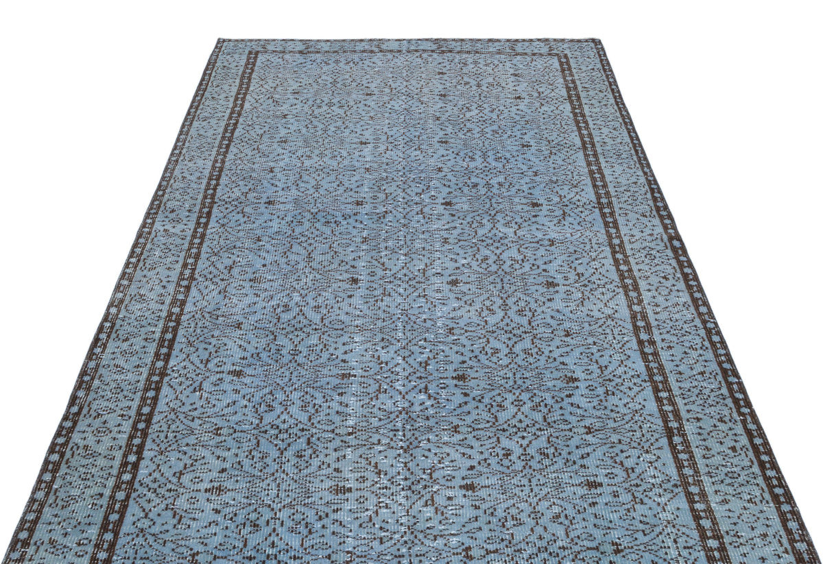 Light blue and dark brown vintage-style rug with an intricate repeating floral pattern and a bordered edge.