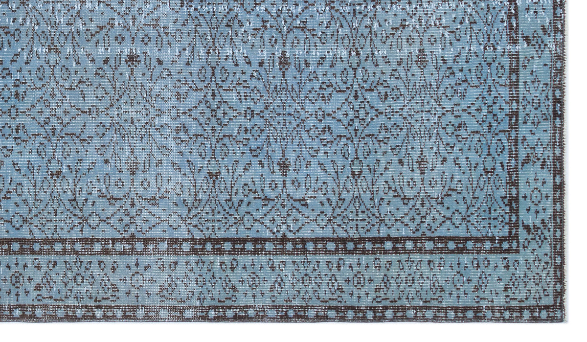 Light blue and dark brown distressed rug with a traditional floral medallion pattern and a geometric border.