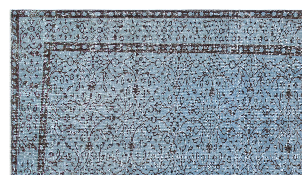 Light blue and dark brown traditional rug with a distressed floral medallion pattern and a geometric border.