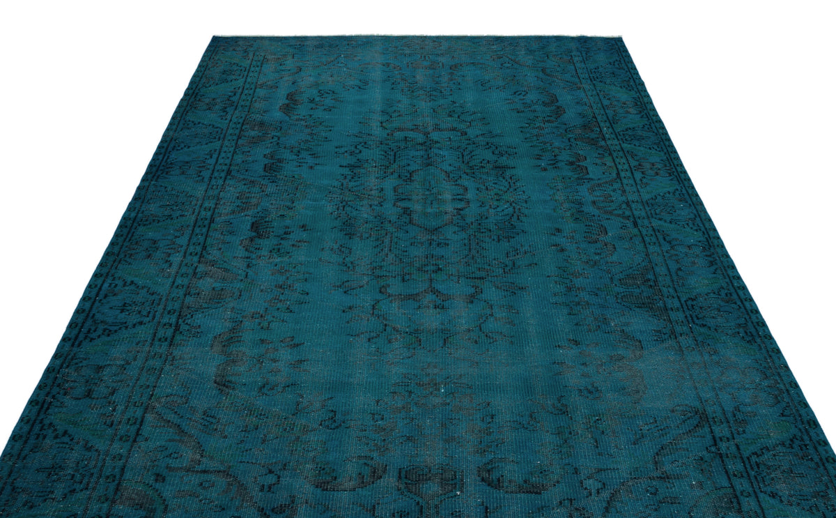 Teal vintage-style rug with a dark, distressed central medallion and ornate border pattern on a white background.