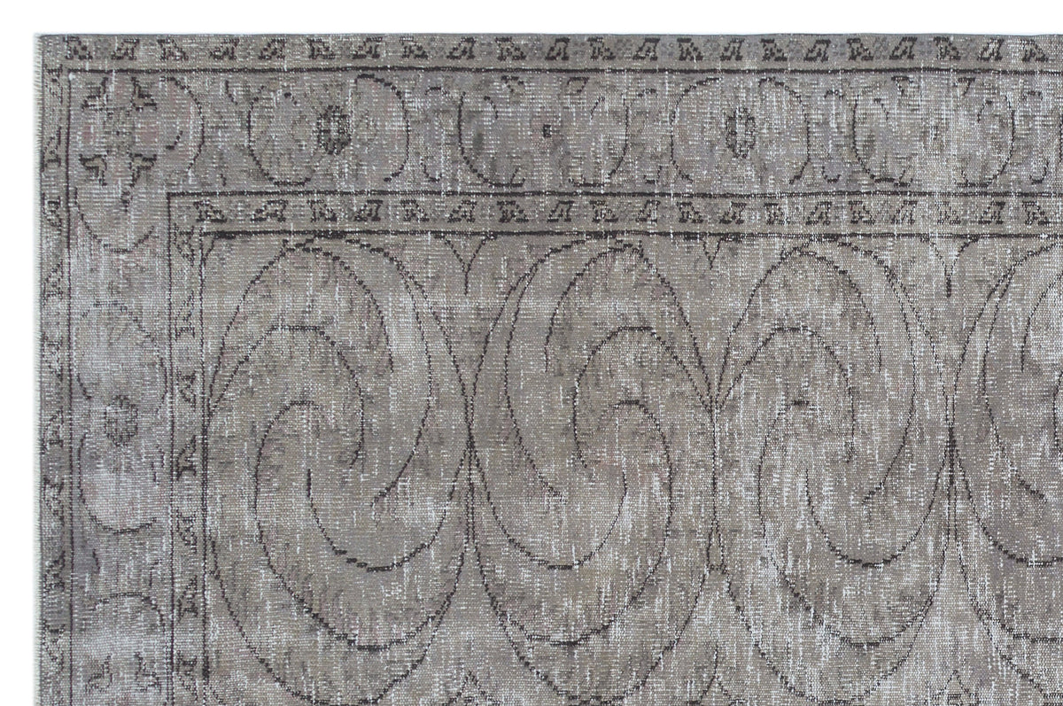 Distressed taupe and grey rug with a large-scale swirling floral medallion pattern and a decorative border.