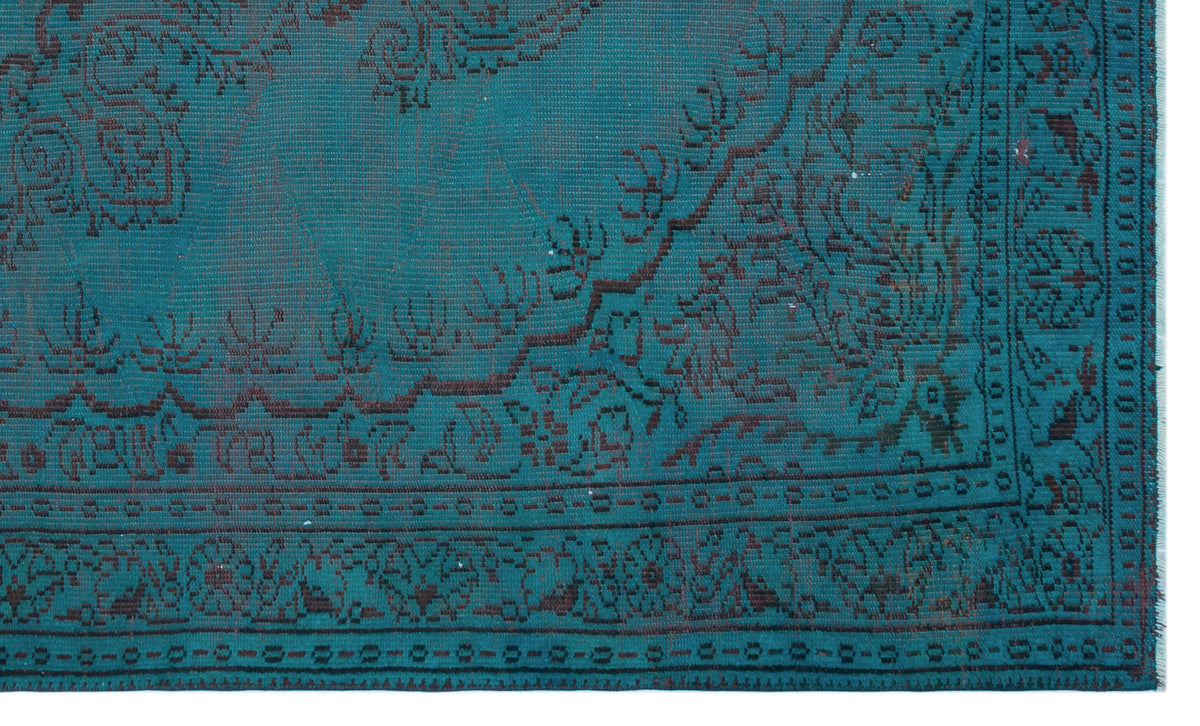Teal rug with a dark brown traditional floral medallion pattern and a geometric border.