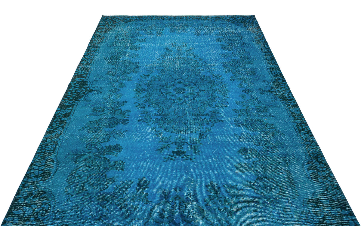 Bright blue distressed area rug with a dark central floral medallion and ornate border on a white background.