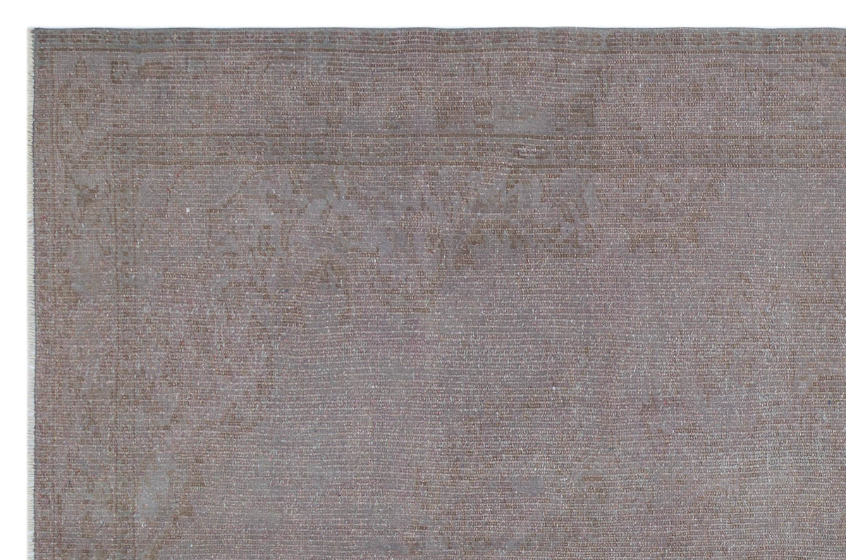 Muted taupe and grey distressed rug with a faint, traditional overdyed medallion pattern.
