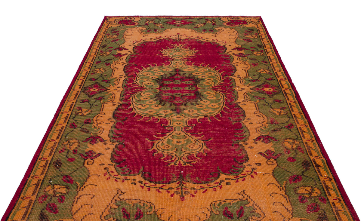 Red, orange, and green traditional rug with a central floral medallion and ornate border on a white background.