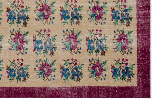 Load image 1 in gallery view. Beige rug with a repeating floral pattern in blue, magenta, and green, framed by a wide, distressed magenta border.